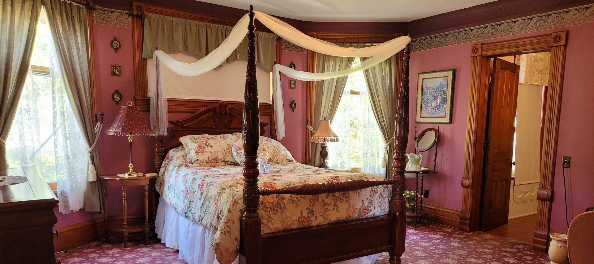 Elegant guest room in a historic home with a four poster bed, red walls and patterned carpet