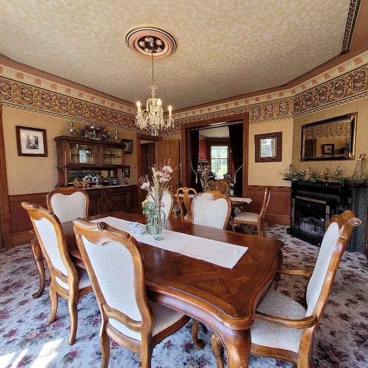 Dining room with two tables with chairs, fireplace, large buffet and doorway into a second room