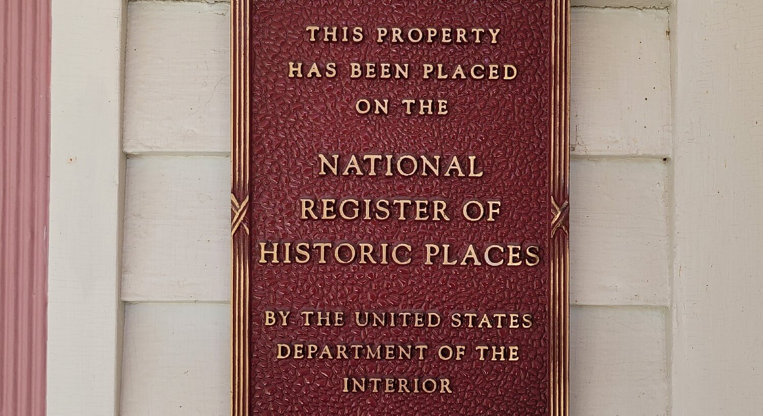 Red sign posted on the front of a home stating historical registry