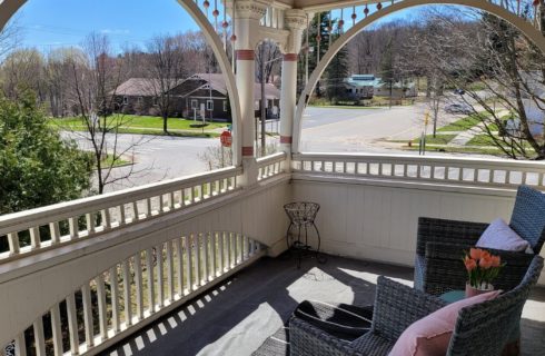 Outdoor upper level patio with wicker chairs and arched openings overlooking a street corner