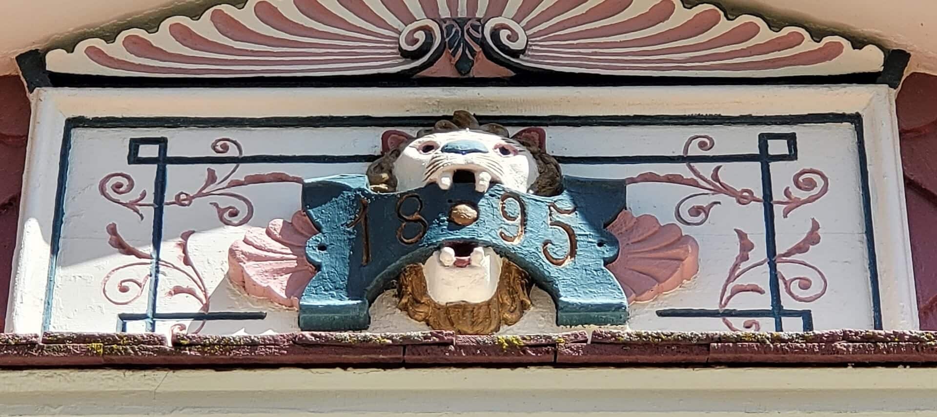 Decorative lion head over a doorway with the year 1895 showing historical significance