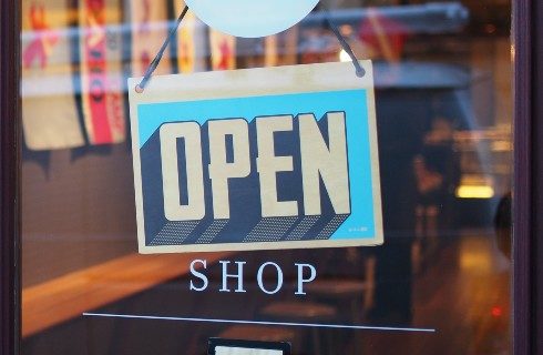 An open sign hanging on the window of store front