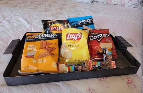 Metal tray of various snacks sitting on the edge of a quilted bed
