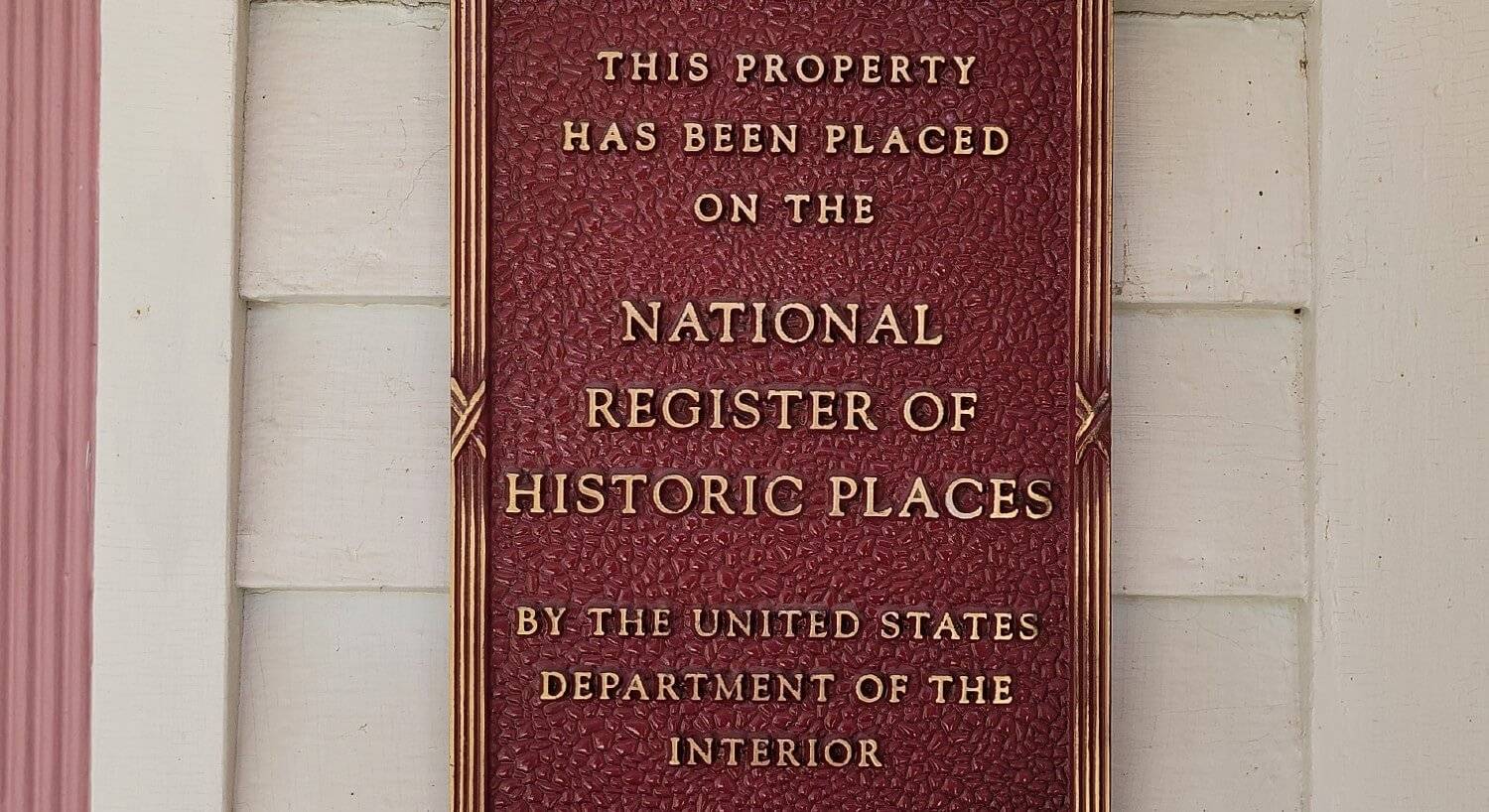 Red sign posted on the front of a home stating historical registry