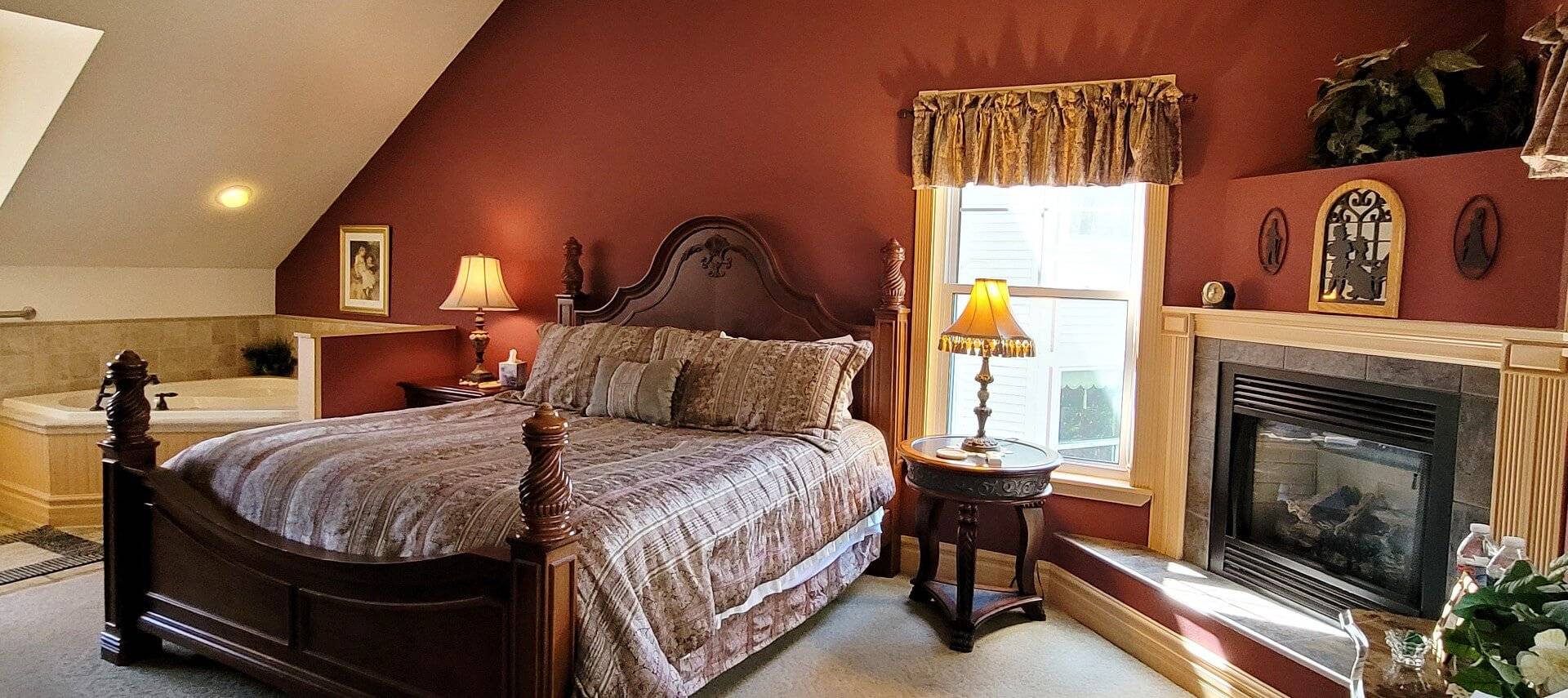 Spacious bedroom with fireplace, queen bed, large corner soaker tub and bright window