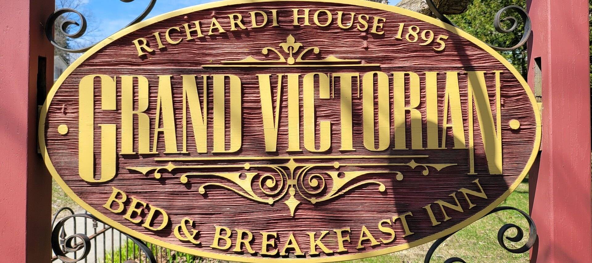 Red and gold oval business sign with black scroll details